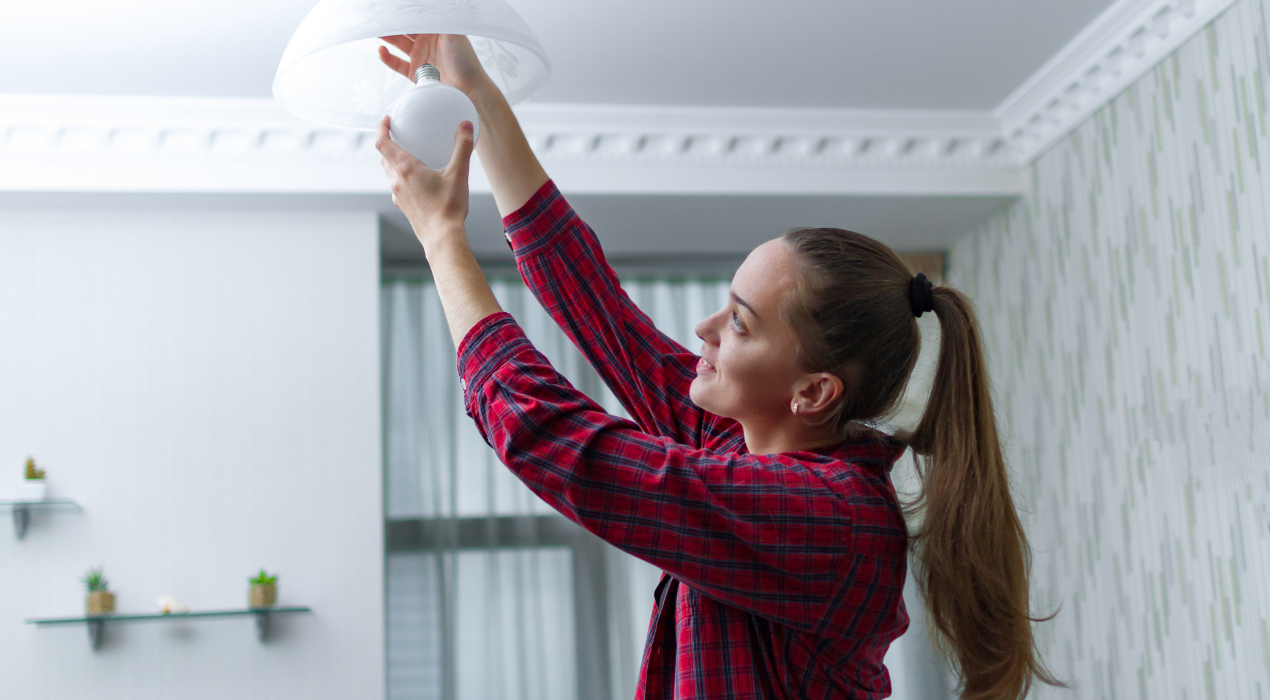 Girl with ponytail fixing light bulb