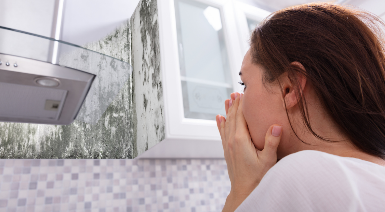 Woman in kitchen looking at mold on cabinets and walls