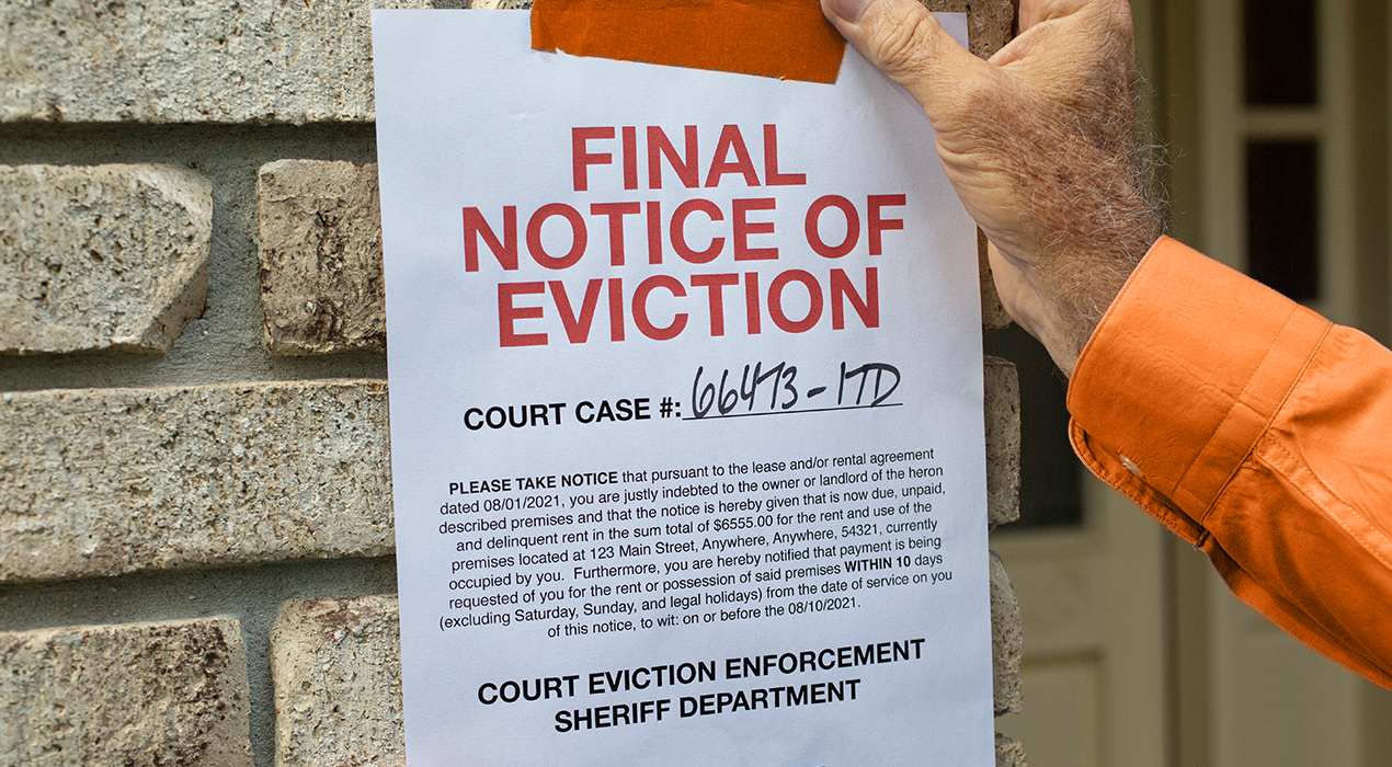 Final notice of eviction with hand in orange long sleeves